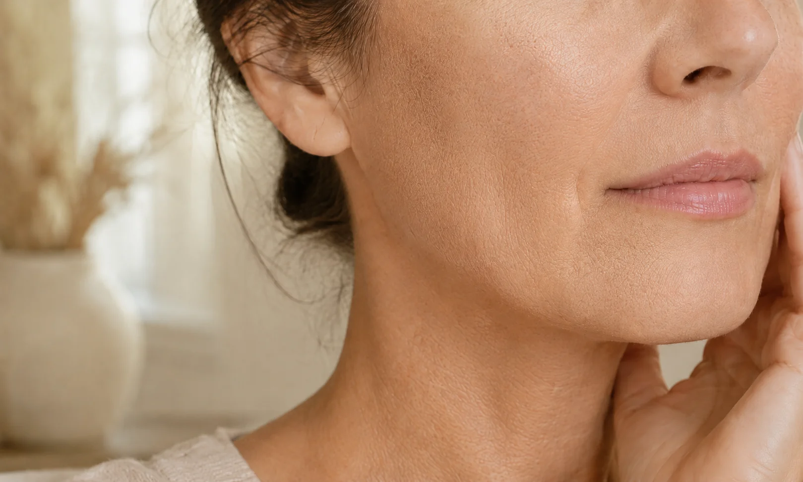 Close-up of a woman’s cheek and neck showing natural skin texture and a slightly dry-looking complexion.