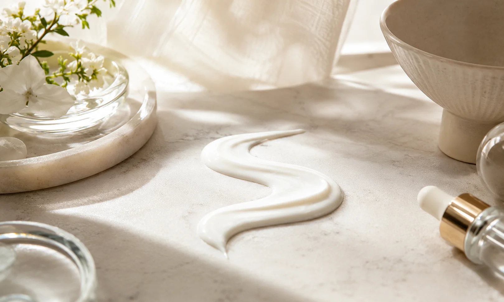 Sunscreen-style cream texture with skincare dropper, soft sunlight, and white flowers on a neutral spa surface